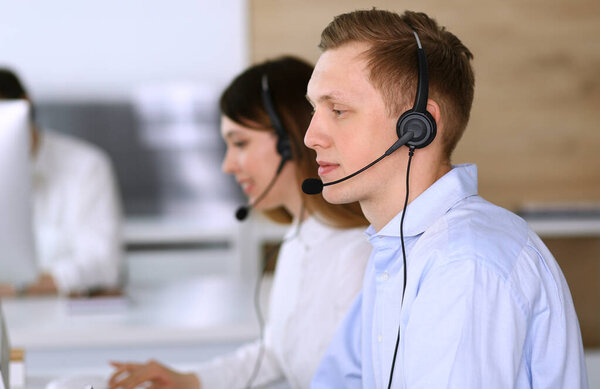 Call center. Group of diverse operators at work. Focus on businessman in headset at customer service office. Business concept