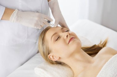 Güzellik doktoru, beyaz kadın yüzüne şırıngayla güzellik prosedürü uyguluyor. Kozmetik tıp ve cerrahi, güzellik enjeksiyonları konsepti