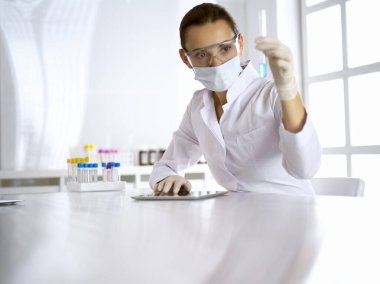 Kadın laboratuvar asistanı mavi sıvıyla test tüpünü analiz ediyor. Tıp, sağlık ve araştırma konsepti