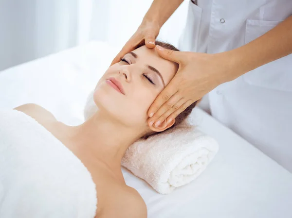 Jonge en blonde vrouw geniet van gezichtsmassage in spa salon. Schoonheidsconcept — Stockfoto