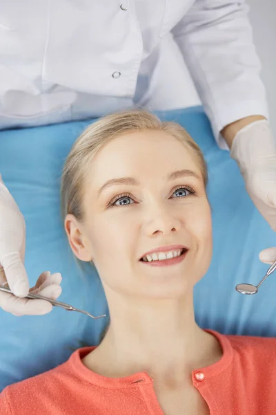 Uśmiechnięta biała kobieta jest badana przez dentystę w klinice stomatologicznej. Zdrowe zęby i medycyna, koncepcja stomatologii — Zdjęcie stockowe