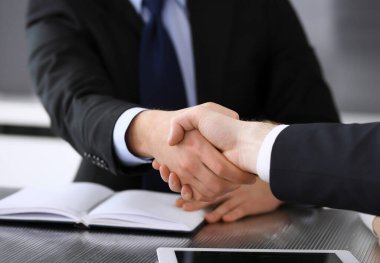 İş adamı, modern ofiste iş arkadaşı veya ortağıyla el sıkışıyor. Yakın plan. Toplantıda bilinmeyen iş adamları var. Takım çalışması, ortaklık ve el sıkışma kavramı