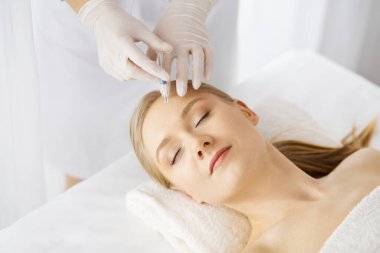 Güzellik doktoru, beyaz kadın yüzüne şırıngayla güzellik prosedürü uyguluyor. Kozmetik tıp ve cerrahi, güzellik enjeksiyonları konsepti