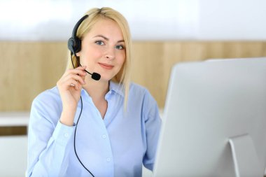 Merkezi ara. Müşteri hizmetleri ofisinde kulaklık takan sarışın bir iş kadını. Telesellerin iş ya da ev işgali kavramı