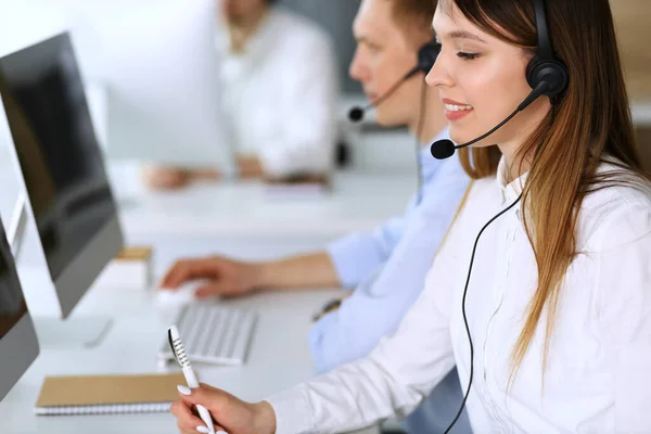 Centro de llamadas. Grupo de operadores diversos en el trabajo. Enfócate en la hermosa mujer asiática con auriculares en la oficina de servicio al cliente. Concepto empresarial — Foto de Stock