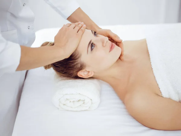 Jonge en blonde vrouw geniet van gezichtsmassage in spa salon. Schoonheidsconcept — Stockfoto