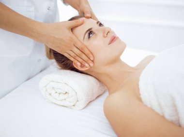 Genç ve sarışın kadın spa salonunda yüz masajından zevk alıyor. Güzellik konsepti