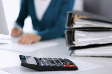 Hesap makinesi ve kağıtlar iş kadını ya da ofisteki büroda çalışan muhasebeci tarafından incelenmeyi bekliyor. İç Denetim ve vergi kavramı