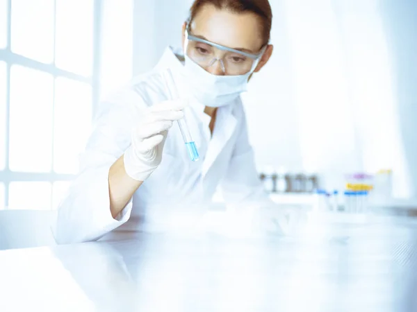 Female laboratory assistant analyzing test tube with blue liquid. Medicine, health care and researching concept — Stock Photo, Image