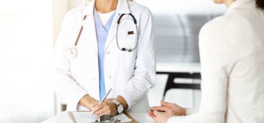 Sunny Hastanesi 'nde bilinmeyen bir kadın doktor ve hasta var. Doktor ilaç geçmişi kayıtlarını ve sınav sonuçlarını kontrol ederken pano kullanıyor, yakın plan.