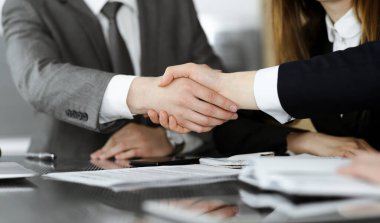 Bilinmeyen işadamı, modern ofiste iş arkadaşı ya da ortağıyla el sıkışıyor. Toplantıda iş adamları grubu