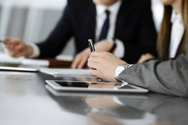 Bilinmeyen iş adamları ve kadınlar oturmuş, dizüstü bilgisayarlarını kullanıyorlar ve modern ofiste buluşmada soruları tartışıyorlar, yakın plan.