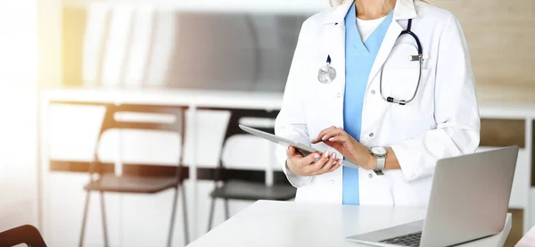 Femme-médecin inconnue au travail dans une clinique ensoleillée. Médecin femme utilisant un ordinateur tablette, gros plan — Photo