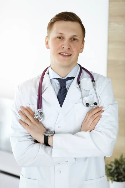 Man-dokter staat recht in een zonnige kliniek. Geneesmiddelenconcept — Stockfoto