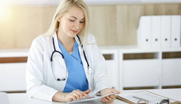 Mujer-médico sentado en la clínica soleada y el uso de la tableta PC. Datos y mejor servicio en medicina y salud — Foto de Stock