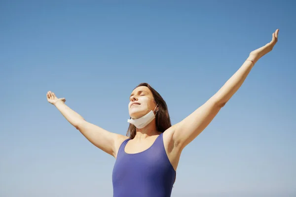 Coronavirus salgınında yaz tatili. Yüz maskesi şeklinde güneş yanığıyla yükselen kadın elleri.