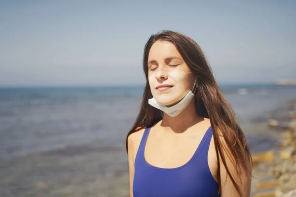 Sahilde Güneş yanığı olan Maskeli Kadın. Coronavirüs Salgınında Yaz Tatili. 