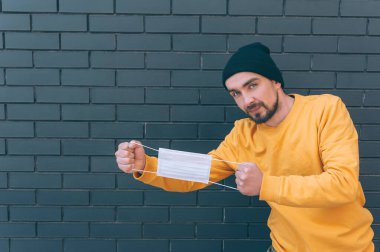 Genç bir adam elinde tıbbi bir maske tutuyor. Koruma ve Önleme COVID-19