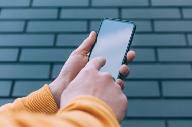 Model teknolojisi. Adam akıllı telefonu yakın planda tutuyor.