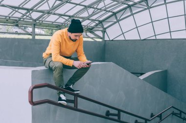 Sarı kazaklı adam sokakta akıllı bir telefonla konuşuyor.