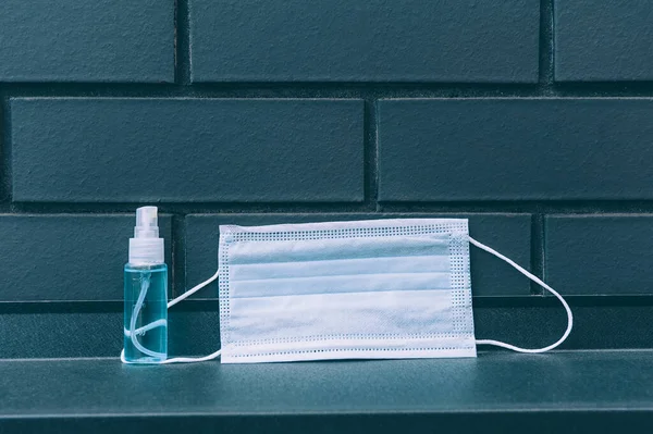 Hygiene and protection of the face and hands from the virus. Spray antiseptic and medical masks on a brick background