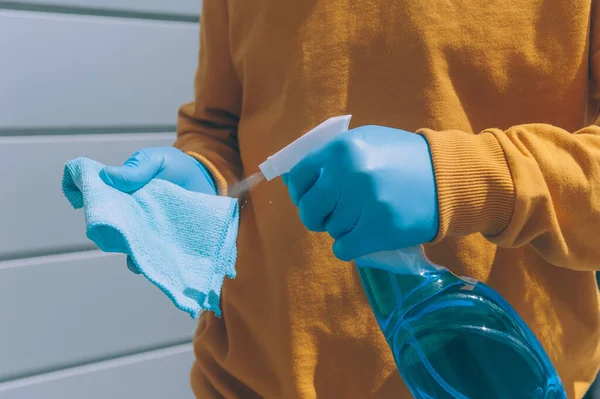 Genç bir adam elinde bez parçasıyla mavi bir antiseptik ile tırabzanı dezenfekte ediyor. COVID-19 'dan koruma ve önleme