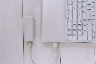 Laptop, tahta arka planda taşınabilir şarj cihazını şarj ediyor.