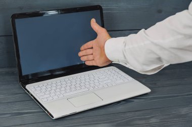 Elinde dizüstü bilgisayarla gri arka planda mavi ceketli bir iş adamı.