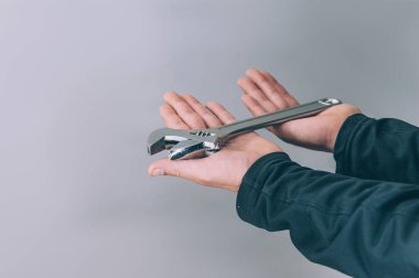 Bir adam elinde iş için bir ingiliz anahtarı tutuyor.