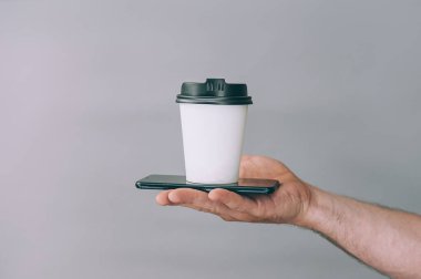 Logo ve tasarım için bir model. Bir adam elinde akıllı telefonlu bir bardak kahve tutuyor.