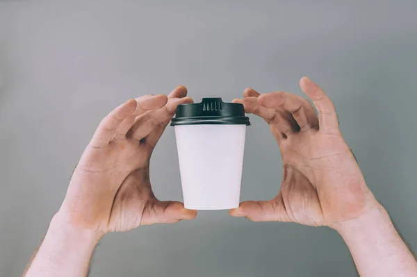 Mock-up for logos and design. A man holds in his hand a glass of coffee