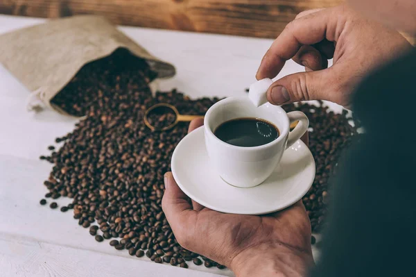 The guy holds in his hands a coffee cup on a background of beans