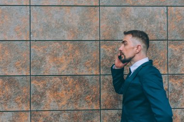 Mavi ceketli bir iş adamı ve arka planında bir akıllı telefon var.