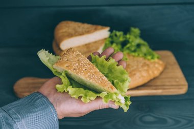 Marul yaprakları ve ahşap bir masa üzerinde eli olan bir adam.