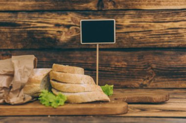 Kağıt ambalajda marullu taze ekmek, yanmış ahşap bir masanın üzerinde.