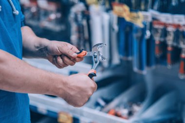 Hırdavatçıdaki alıcı malları seçer. Bir adam elinde İngiliz anahtarı tutuyor.