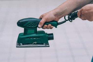 Bir adam elinde odun öğütme makinesi tutuyor. Bir hırdavatçıda alıcı bir ürün seçer