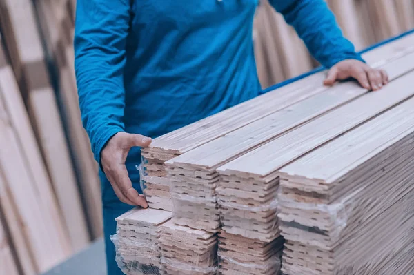 Hırdavatçıdaki bir alıcı bir ürün seçer. Bir adam elinde tahta bir tahta tutuyor.