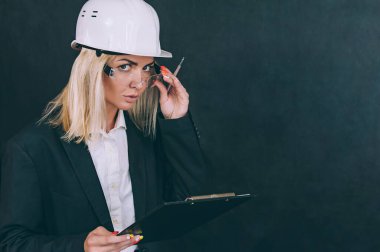 Elinde evrakları ve kafasında miğferi olan bir iş kadını.