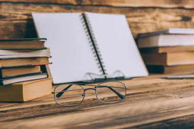 Okula geri dön Mockup. Tahta arka planda kitap ve gözlüklü defter.