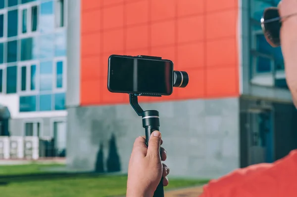 Blogger in the city shoots video on a smartphone with a manual camera stabilizer