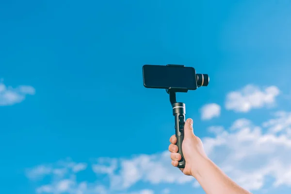 Blogcu, bulutlu bir gökyüzüne karşı el bilgisayarıyla akıllı bir telefonla video çekiyor.