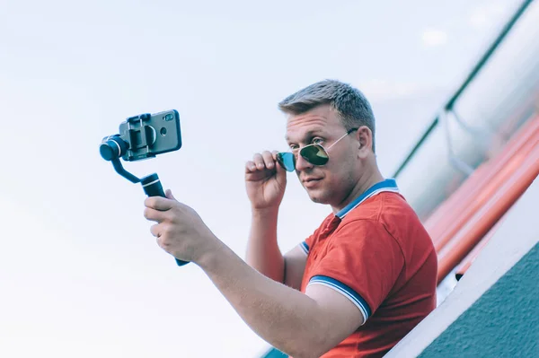 Blogger in the stadium shoots video on a smartphone with a manual camera stabilizer