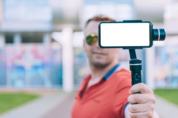 Blogger in the stadium shoots video on a smartphone with a manual camera stabilizer
