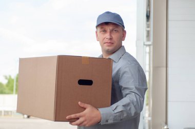 Elinde karton bir kutuyla gri takım elbiseli bir adam. Posta teslimatı konsepti