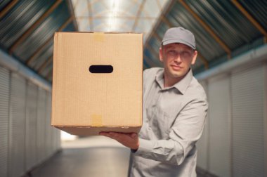 Elinde karton bir kutuyla gri takım elbiseli bir adam. Posta teslimatı konsepti