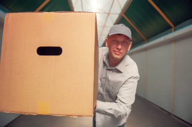 Elinde karton bir kutuyla gri takım elbiseli bir adam. Posta teslimatı konsepti