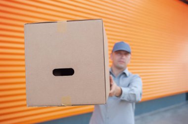 Elinde karton bir kutuyla gri takım elbiseli bir adam. Posta teslimatı konsepti