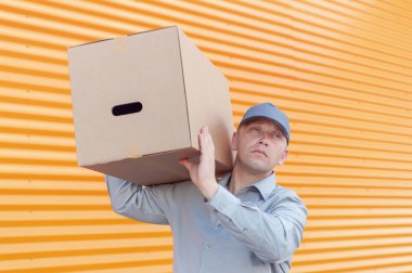 Elinde karton bir kutuyla gri takım elbiseli bir adam. Posta teslimatı konsepti