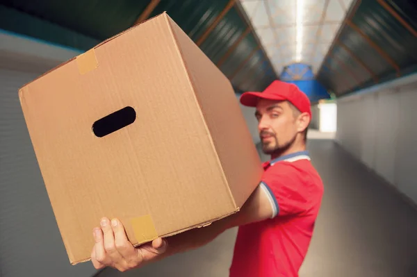 Elinde karton bir kutuyla kırmızı takım elbiseli bir adam. Posta teslimatı konsepti